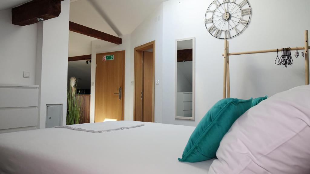 a bedroom with a white bed with a clock on the wall at Apartman Megi & studio apartman Tomi - SELF CHECK IN in Krapina