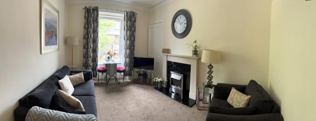 a living room with a couch and a clock on the wall at Cherrybank apartment in Perth