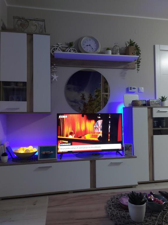 una televisione su un supporto in una cucina con luci viola di # Espresso 2 Apartman sa garazom a Sremska Mitrovica
