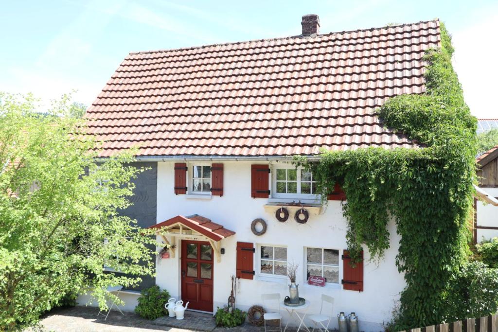 una casa blanca con una puerta roja y hiedra en Linne-Cottage, en Willingen