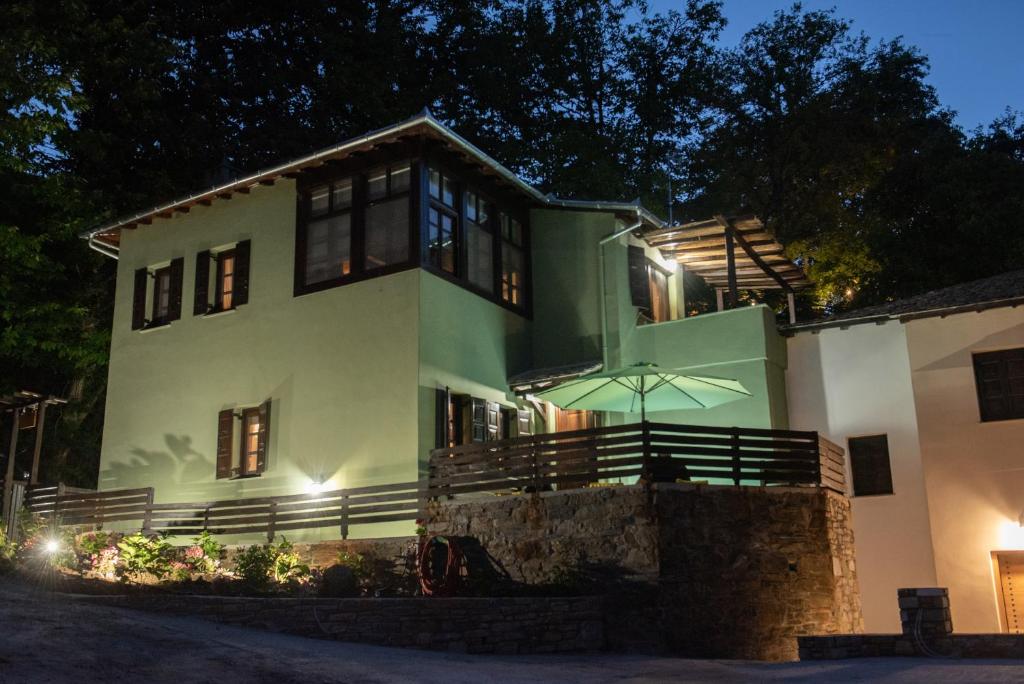 Una gran casa blanca con una sombrilla delante de ella. en Dandy Villas Tsagkarada-Green Apple-Jacuzzi-Sea View, en Tsagkarada