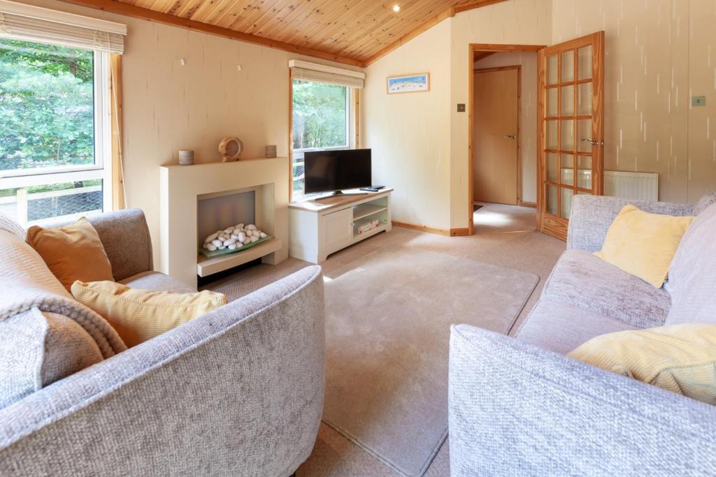 a living room with two couches and a fireplace at Hazel Lodge - Norfolk Cottage Agency in Weybourne