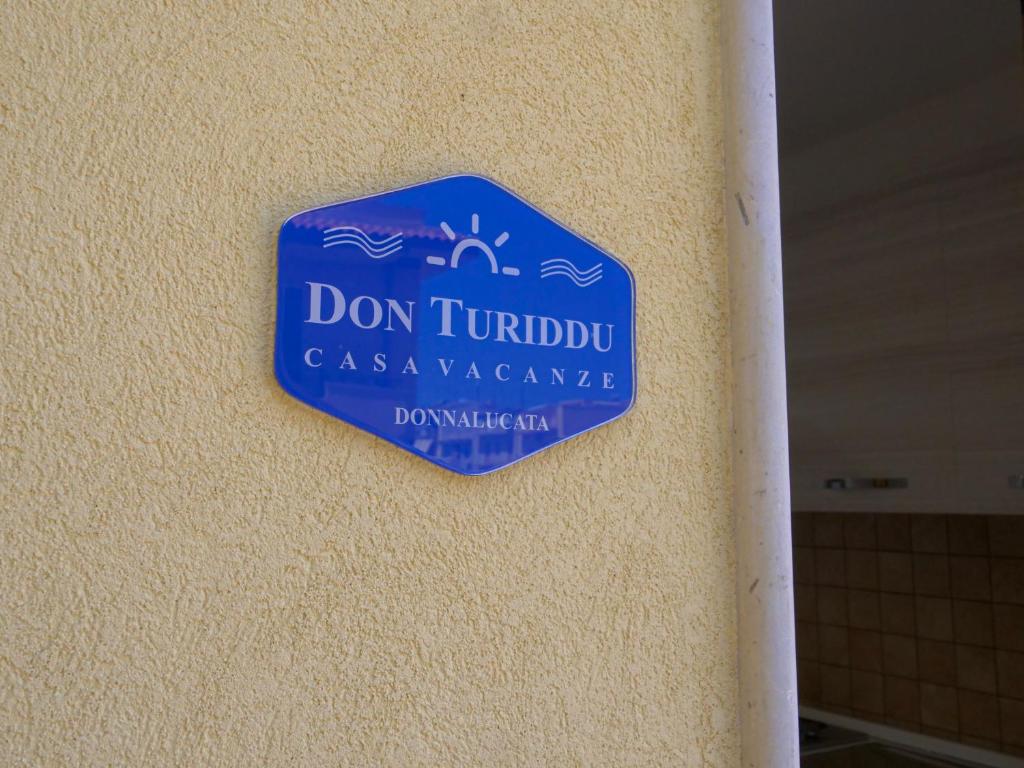 un signe bleu sur le côté d'une paroi dans l'établissement Don Turiddu, à Donnalucata