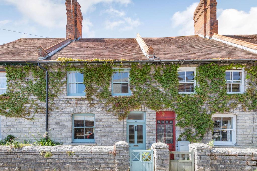 an ivy covered house with a red door at Passiflora Cottage in Swanage