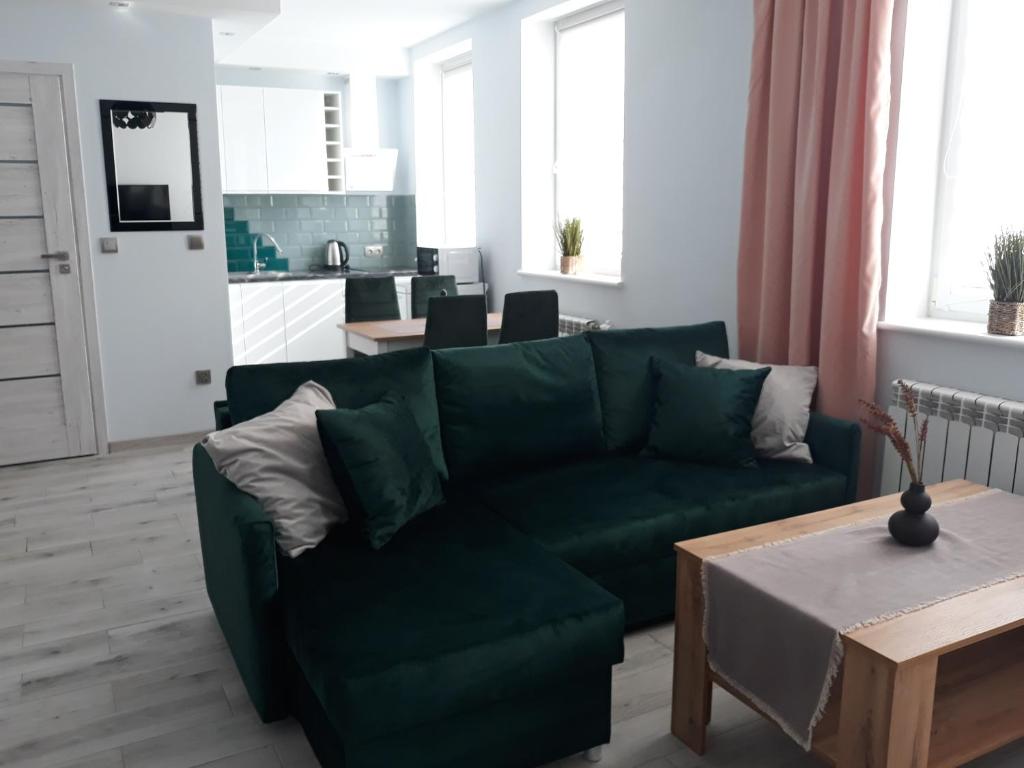 a living room with a green couch and a table at Apartament do wynajęcia in Mikołajki