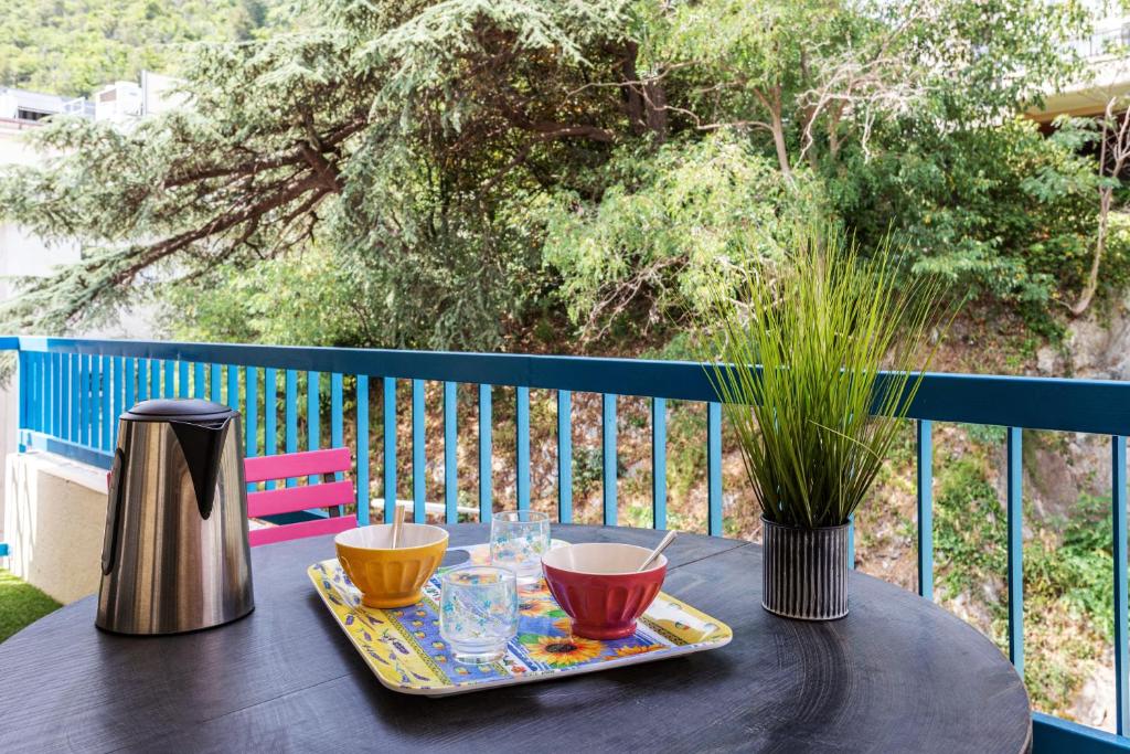 a table with two cups and a thermos on a balcony at Le Balador - 3 étoiles proche thermes in Amélie-les-Bains-Palalda