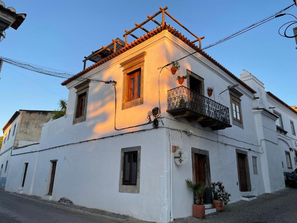 ein weißes Gebäude mit Balkon auf einer Straße in der Unterkunft Casa da Praça - Mourão in Mourão