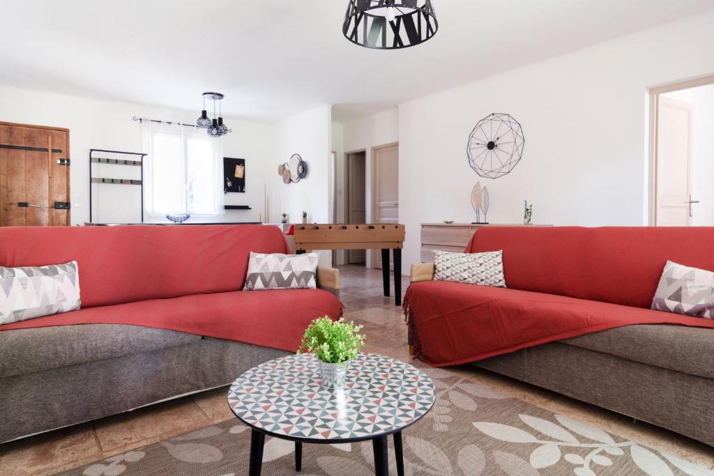 una sala de estar con sofás rojos y una mesa. en Le Mas d'Argens - Maison avec Jardin et Jacuzzi - Accès rivière, en Lorgues