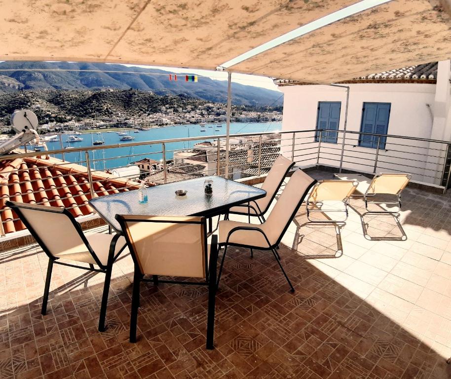 una mesa y sillas en un balcón con vistas en Traditional house with sea view ''MYLOS'', en Poros