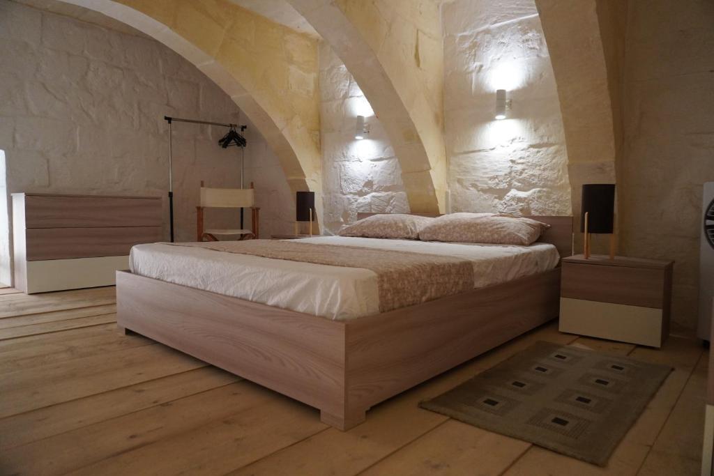 a bedroom with a large bed in a stone wall at Il-Mezzanine in Cospicua
