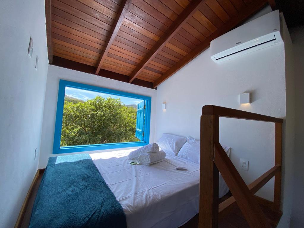 a bedroom with a bed with a large window at Espaço Tropicália in Pirenópolis