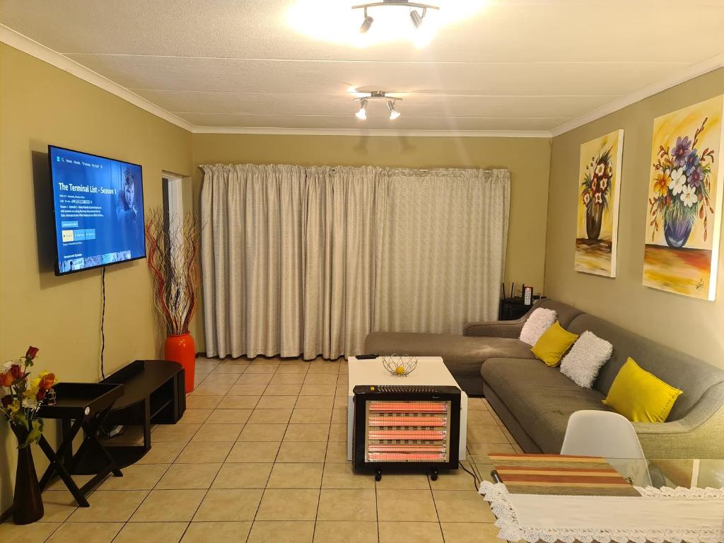 ein Wohnzimmer mit einem Sofa und einem TV in der Unterkunft Midrand Ninth on Lever Shalom in Midrand