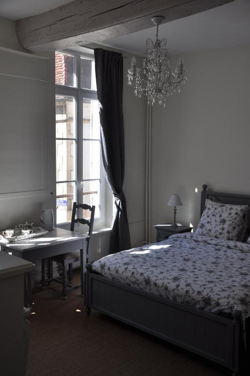 une chambre avec un lit, un bureau et un lustre dans l'établissement B&B Le Relais des Saints Pères, à Auxerre