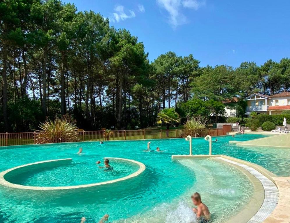 un groupe de personnes nageant dans une piscine dans l'établissement Appartement rénové et cosy dans résidence vacances, à Lacanau-Océan