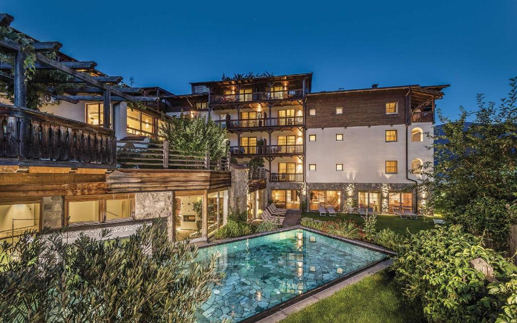 an exterior view of a mansion with a swimming pool at Taubers Unterwirt Aktiv & Vitalhotel in Feldthurns