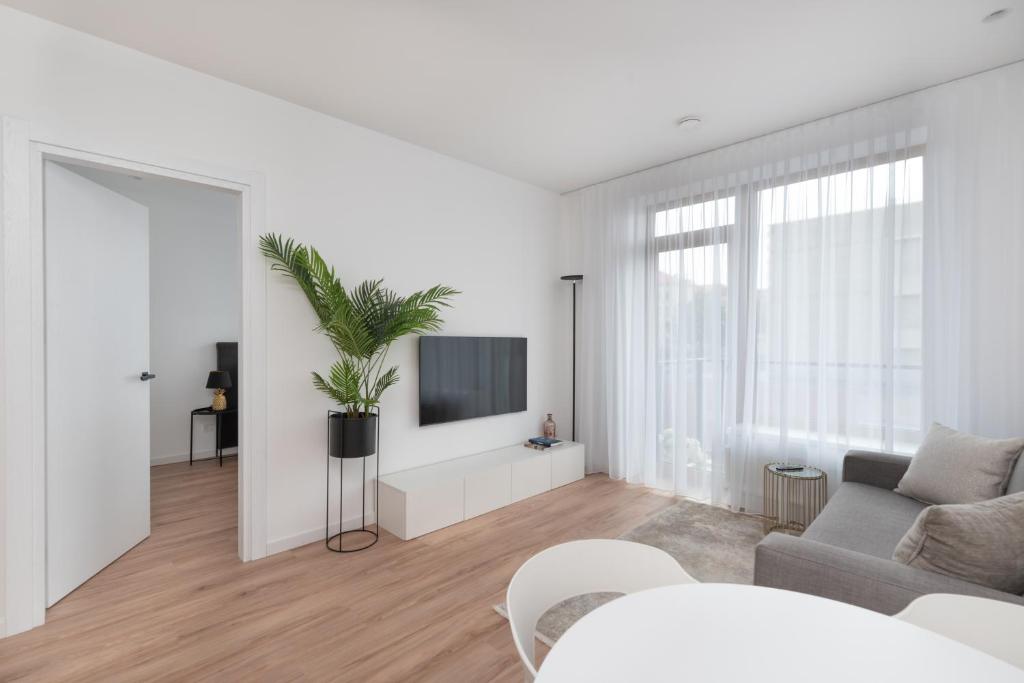 ein weißes Wohnzimmer mit einem Sofa und einem TV in der Unterkunft Brand New and Modern 1BDR Apartment in Vilnius