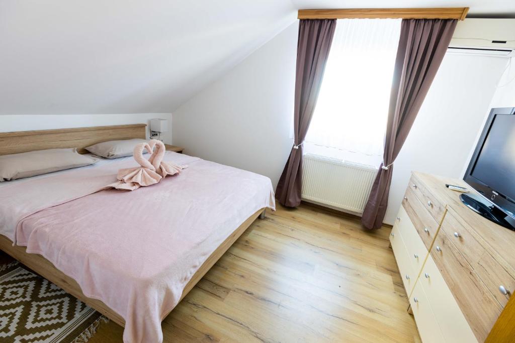 - une chambre dotée d'un lit avec un archet rose dans l'établissement Apartmani Tomšić, à Darda