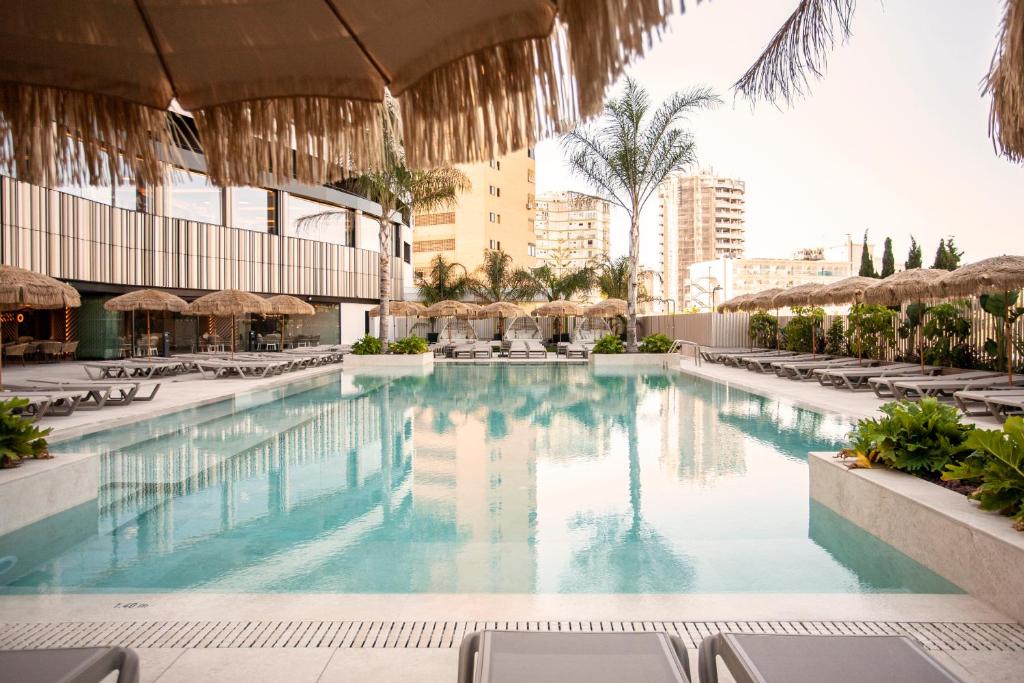 a pool at a resort with chairs and umbrellas at Hotel Primavera Park in Benidorm