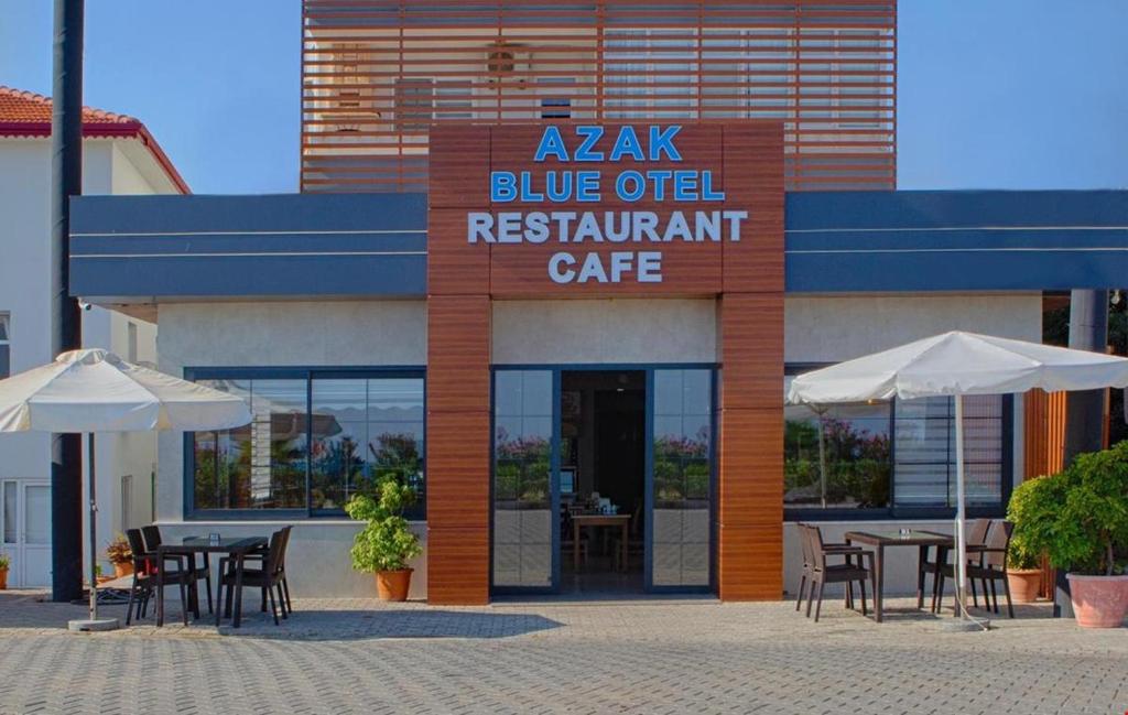 un restaurant avec des tables et des parasols en face d'un bâtiment dans l'établissement AZAK BLUE OTEL, à Okurcalar