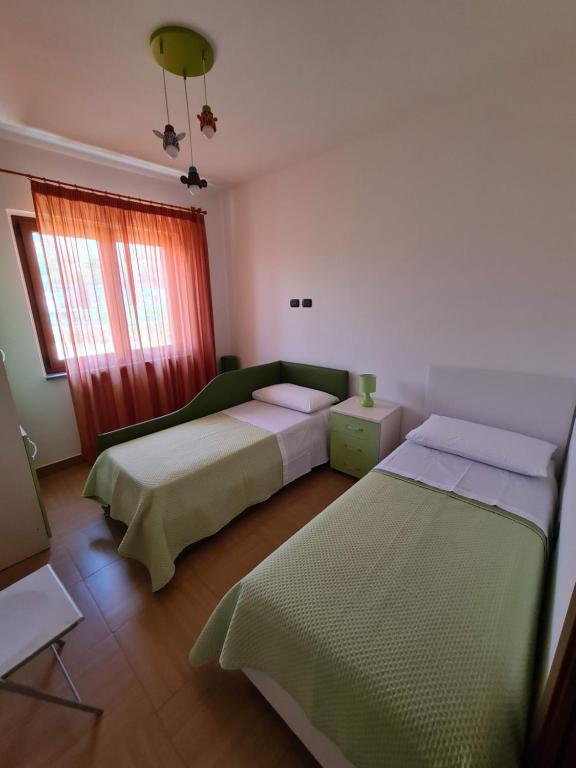 a bedroom with two beds and a window at Diamante 46, Appartamento per vacanza in Diamante