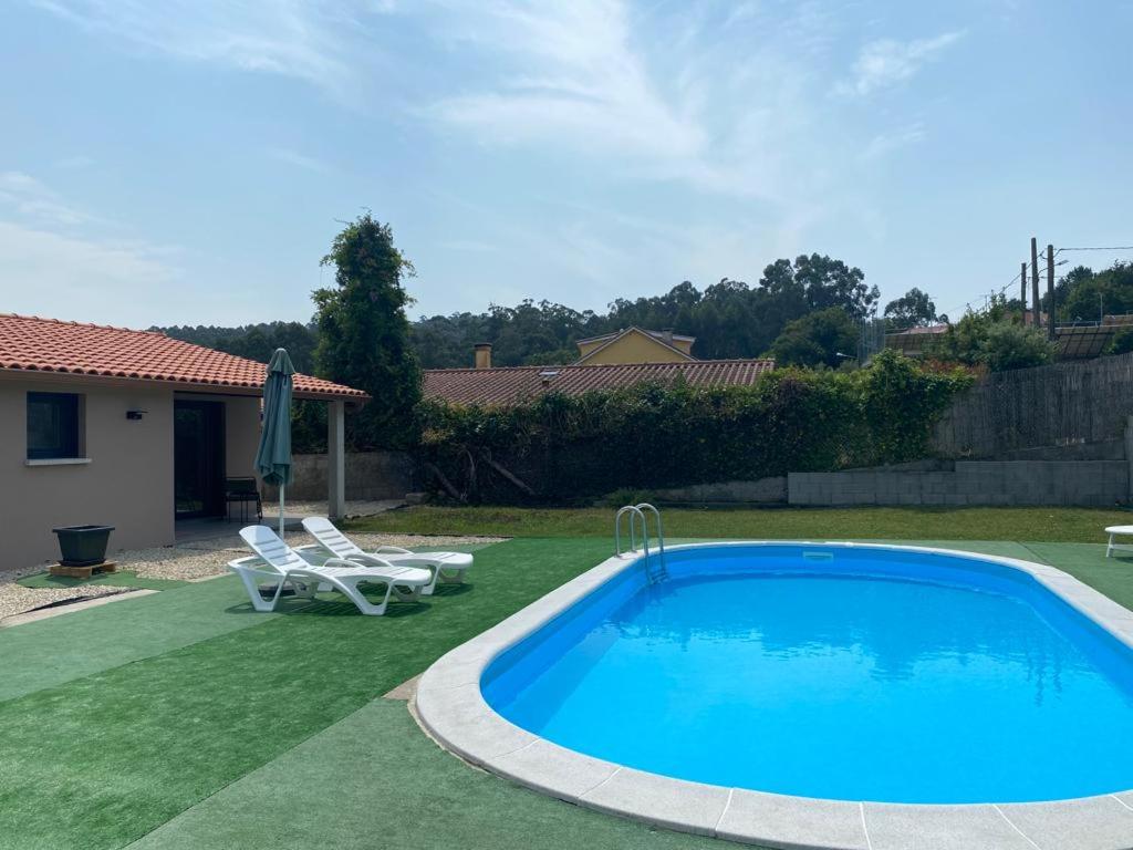 a swimming pool in a yard with two lawn chairs at Acogedora casa de invitados in Bueu