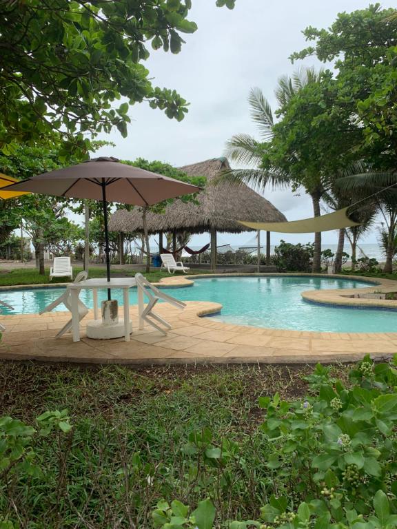 a pool with a table and an umbrella and chairs at Cabo tortuga bungalows in Monterrico