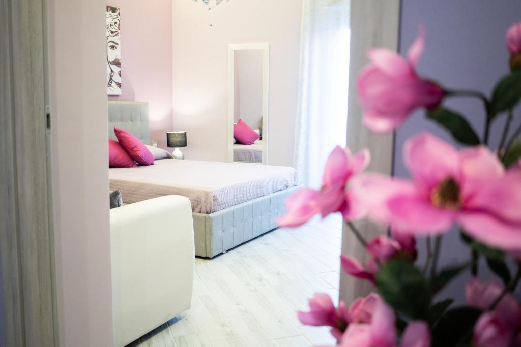 a bedroom with a bed with pink pillows and a mirror at Tyche apartaments & rooms in Taormina