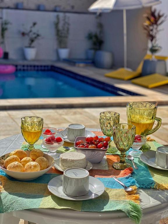 a table with food and drinks and a swimming pool at CASA ALUNAI in Pirenópolis