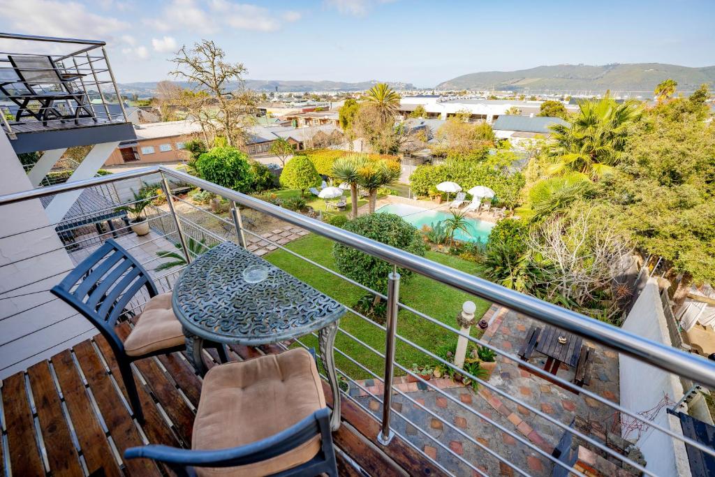 a balcony with a table and chairs and a pool at Aestas Bed and Breakfast in Knysna