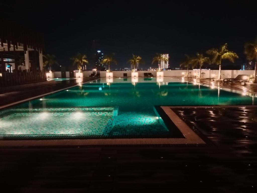una piscina por la noche con luces verdes en Comfortable18 3R2B 7pax Meritus Perai en Perai