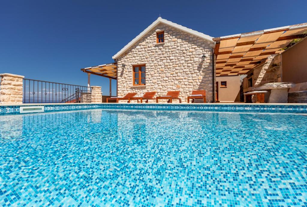 a large swimming pool in front of a house at Seafront Stone Villa in Blato