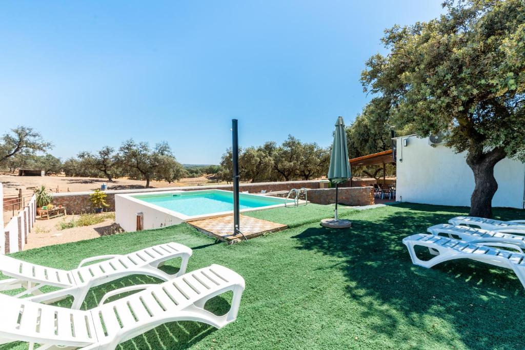 un patio con tumbonas y una piscina en Casa Rural Quejigo con piscina en Santa Olalla del Cala