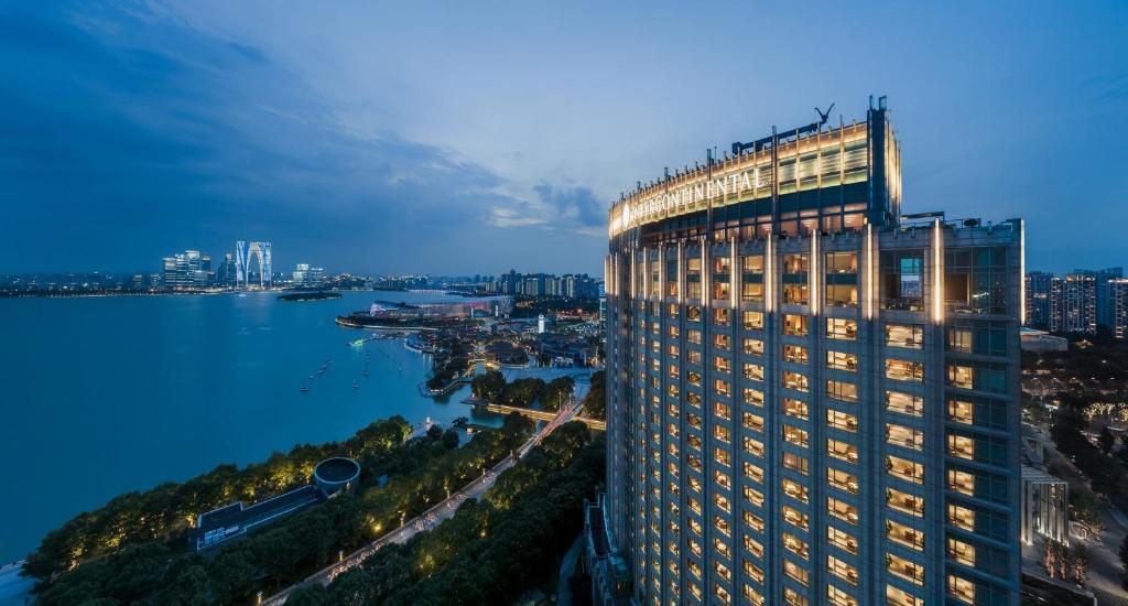 ein hohes Gebäude neben einem Wasserkörper in der Unterkunft InterContinental Suzhou Hotel, an IHG Hotel in Suzhou