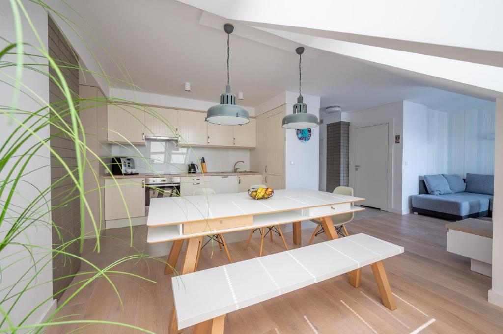 a kitchen and living room with a white table and bench at Apartament Holiday in Darlowko