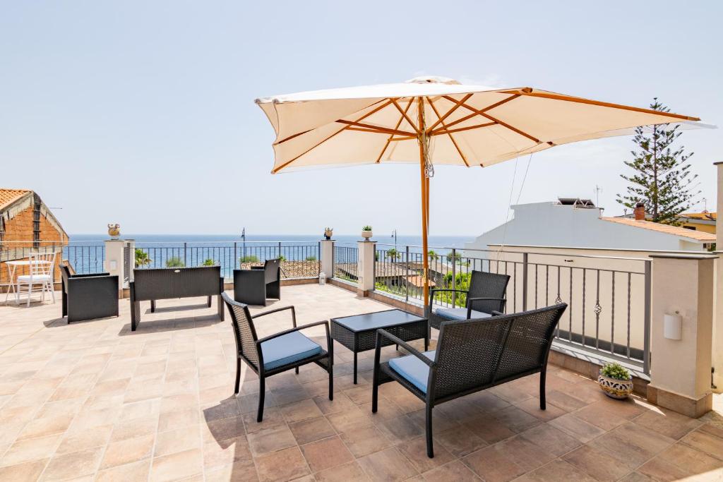 a patio with a table and chairs and an umbrella at Ottocento Sul Mare in Nizza di Sicilia