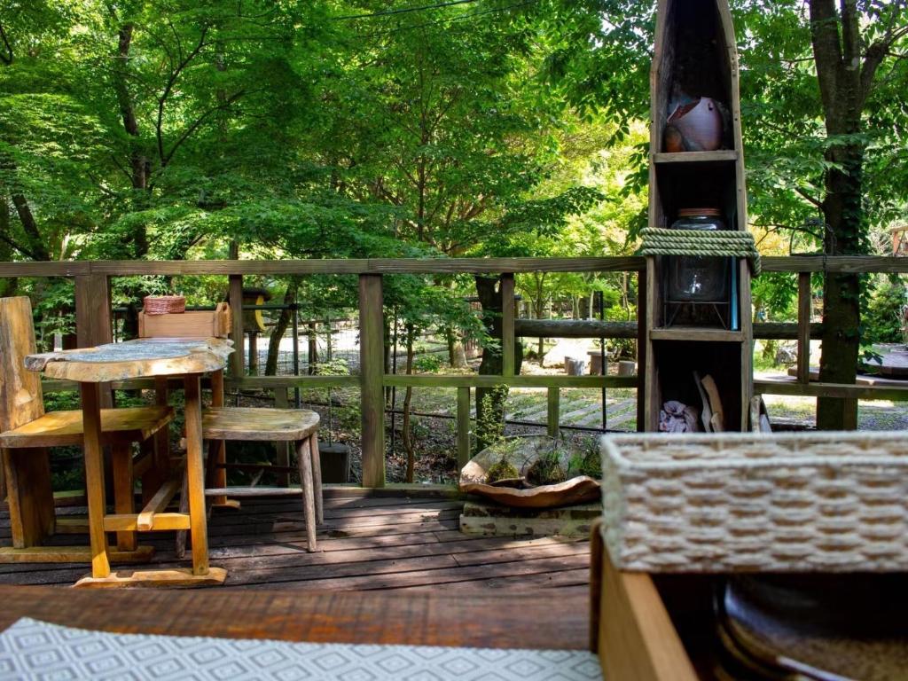 una terraza de madera con mesa, sillas y árboles en Glamping Himeshara - Vacation STAY 01948v, en Kirishima