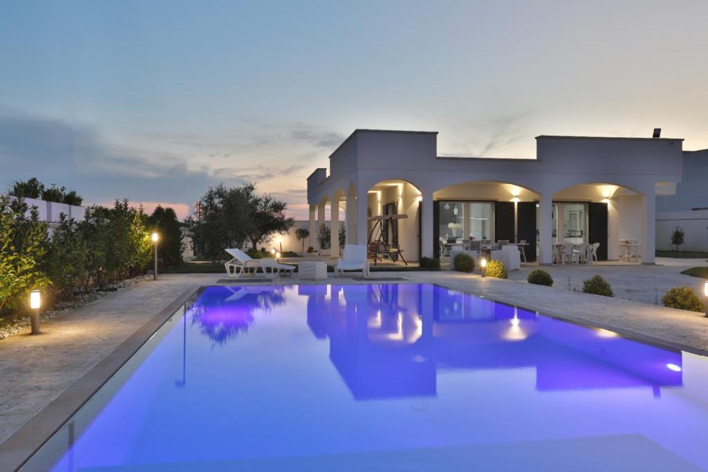 a villa with a swimming pool at night at Villa Alfi in Galatina