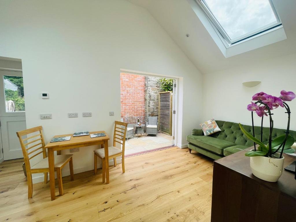 ein Wohnzimmer mit einem grünen Sofa und einem Tisch in der Unterkunft The Garden House in Penzance