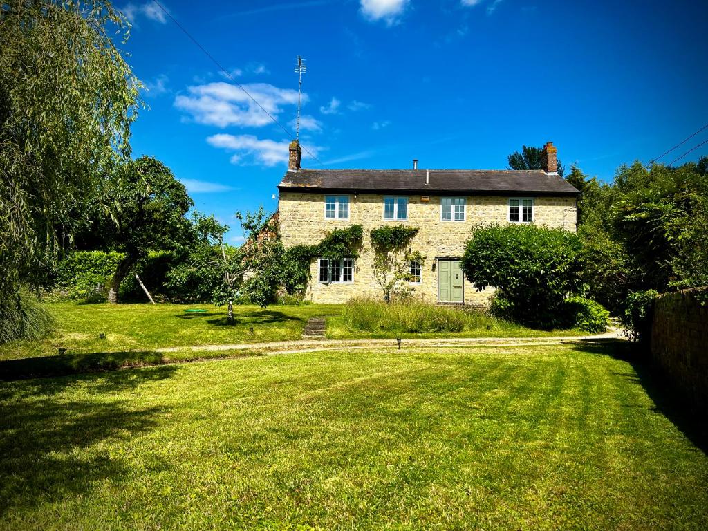 een oud stenen huis op een groen veld bij Home Farm Bed & Breakfast in Milton Keynes