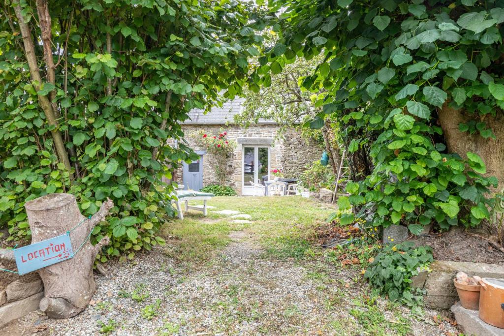 a garden with a stone house with a ivy wall at La Maison des Fées in Pleudihen-sur-Rance