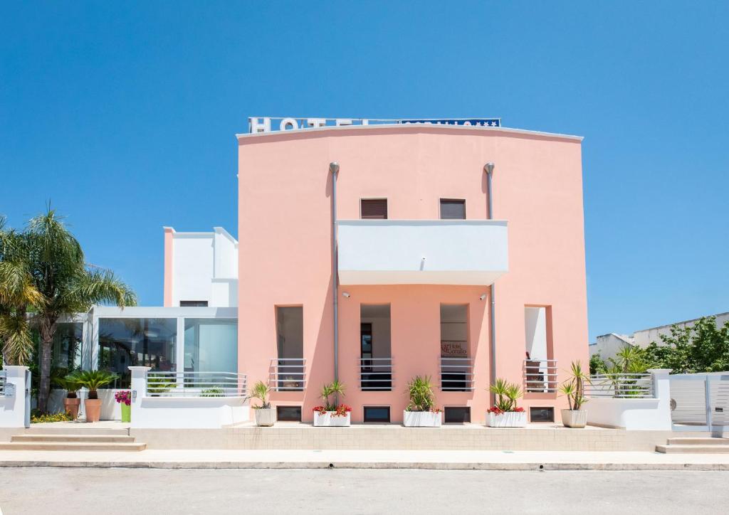 ein rosafarbenes Gebäude mit einem Schild darüber in der Unterkunft Hotel Corallo in Torre Santa Sabina