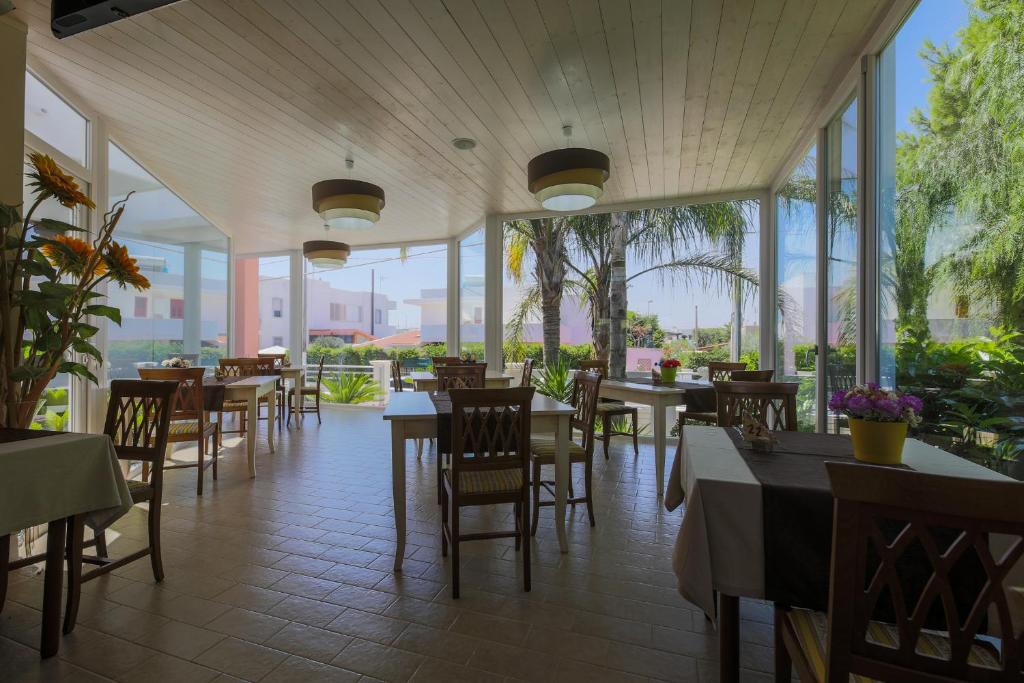 a restaurant with tables and chairs and windows at Hotel Corallo in Torre Santa Sabina