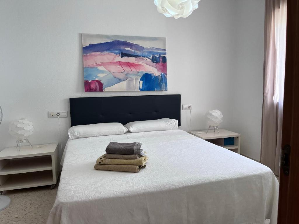 sypialnia z białym łóżkiem i obrazem na ścianie w obiekcie Apartamento céntrico en Tarifa. w mieście Tarifa