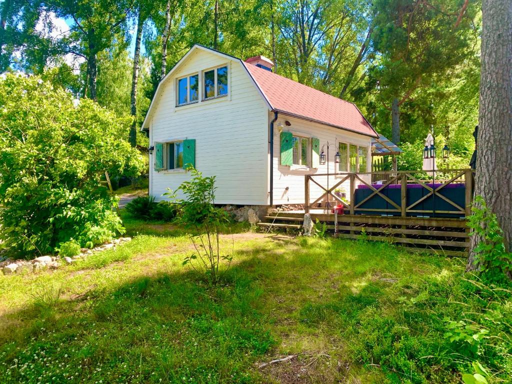 una pequeña casa blanca en medio de un patio en Charmig stuga av rustik stil i Stockholms område en Estocolmo