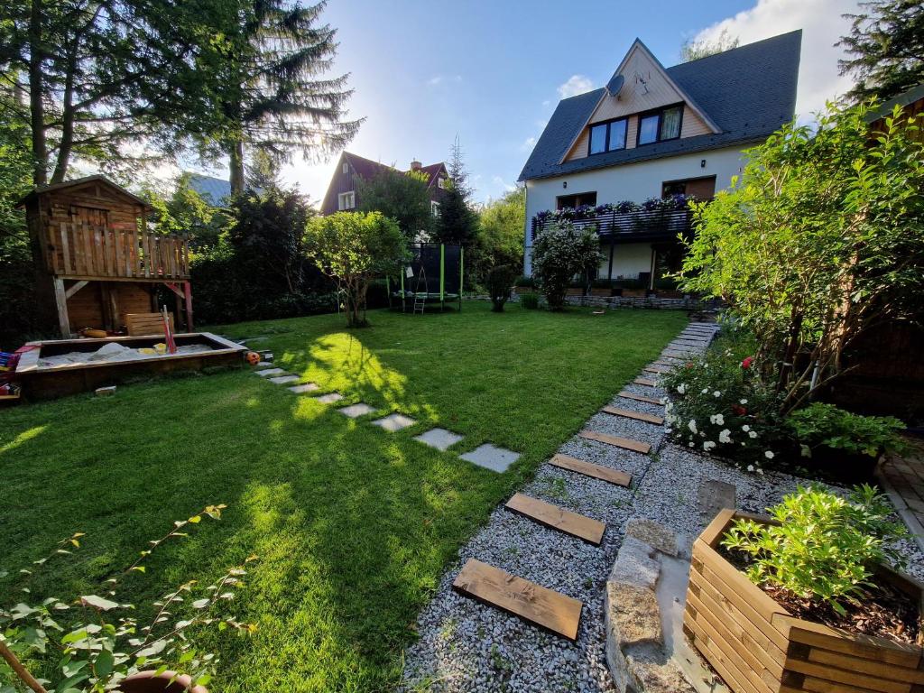 a backyard with a house and a yard with a lawn sidx sidx sidx at Apartamenty przy Świerku in Szklarska Poręba