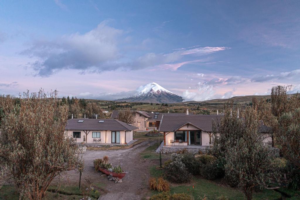 una montaña cubierta de nieve en la distancia detrás de las casas en Chilcabamba Lodge, en Machachi