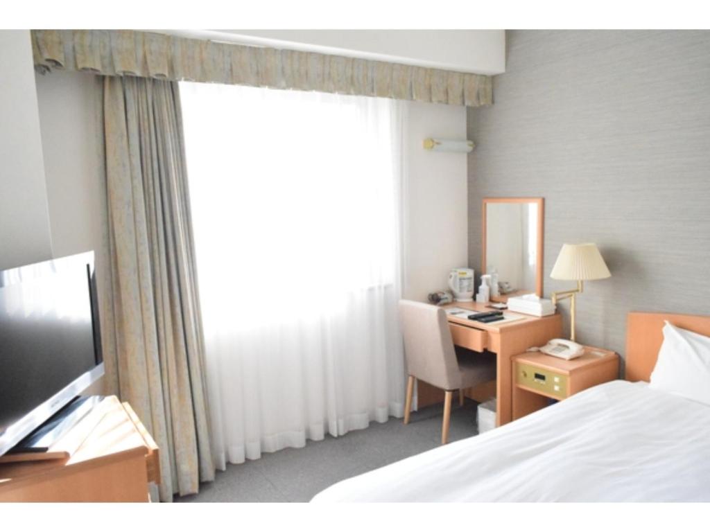 a hotel room with a bed and a desk and a window at Bright Park Hotel - Vacation STAY 67876v in Kochi