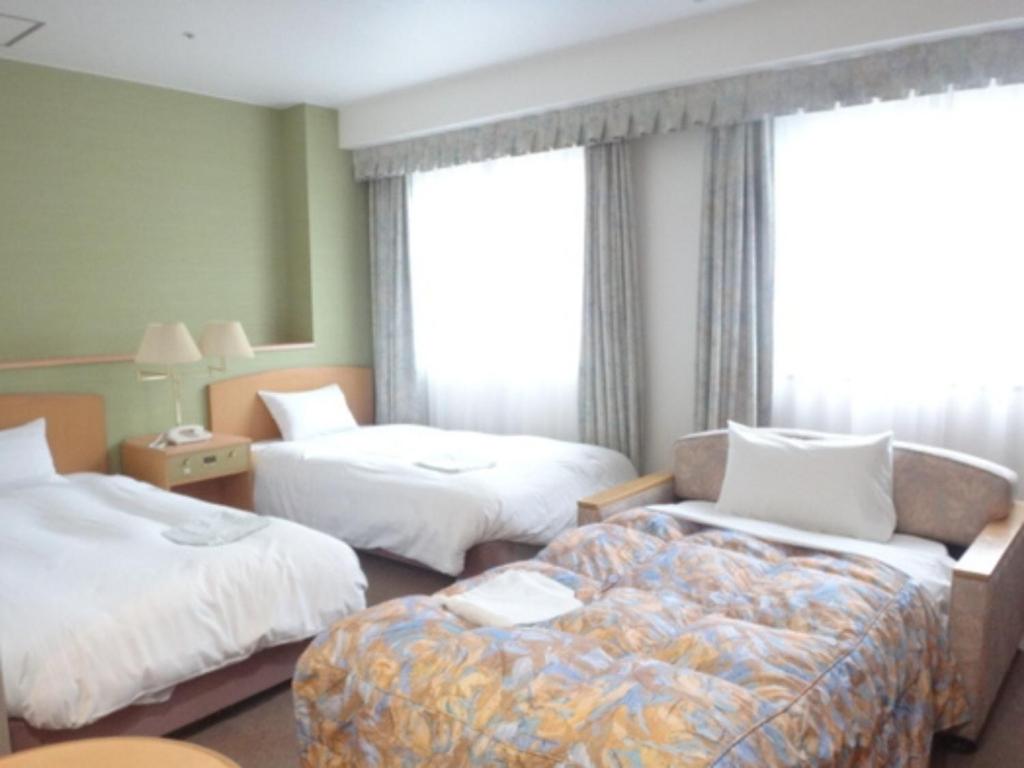 een hotelkamer met 2 bedden en een bank bij Bright Park Hotel - Vacation STAY 67869v in Kochi