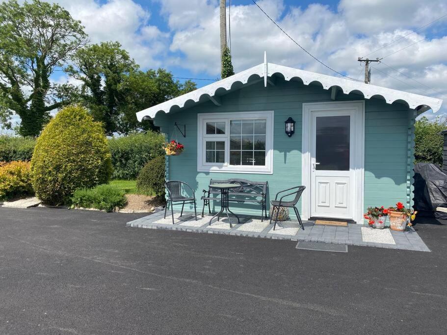 una pequeña casa azul con mesa y sillas en Adorable Cabin in the Countryside, en Portlaoise
