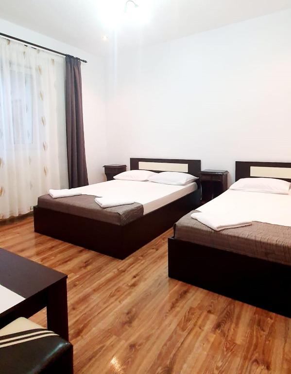 two beds in a room with wooden floors at Casa Eduard in Eforie Sud